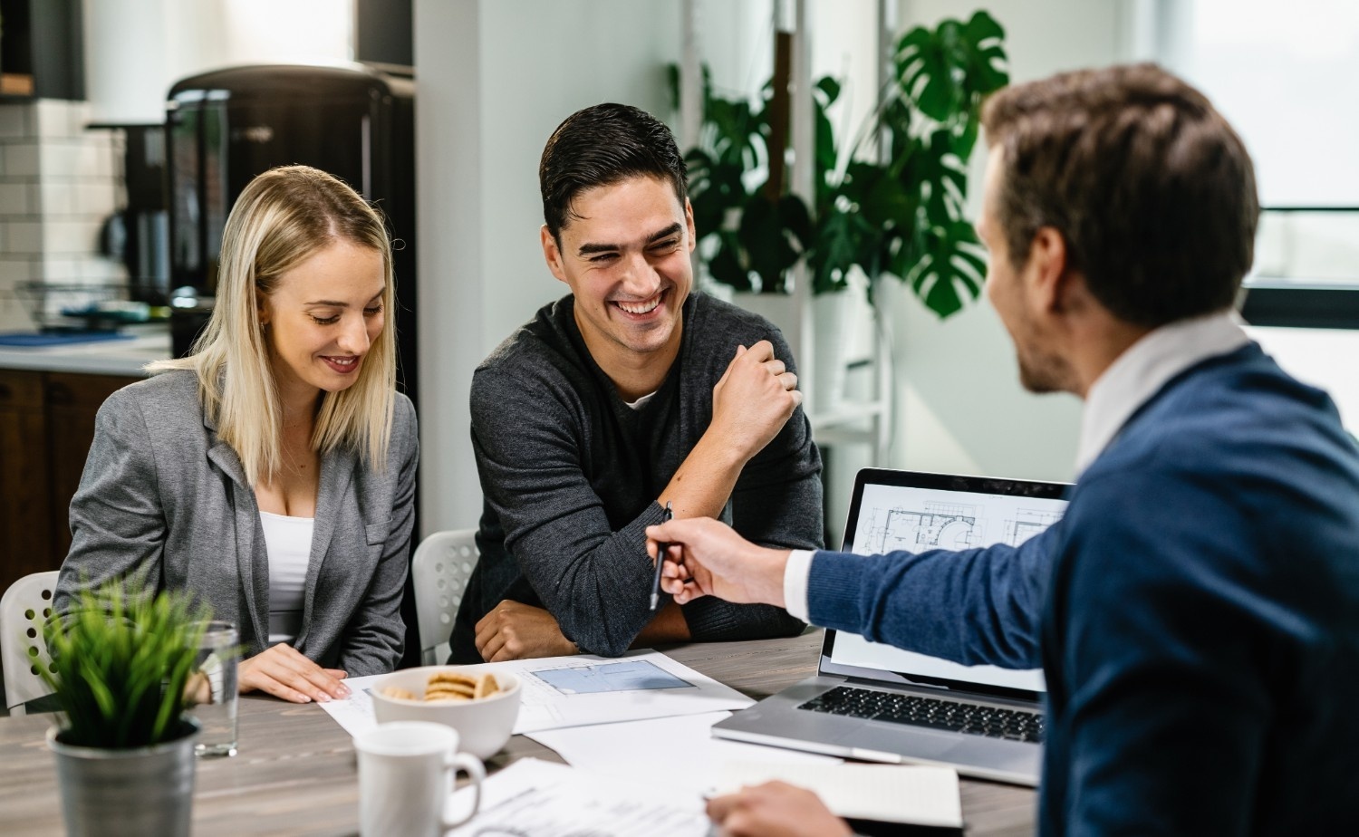 happy-couple-having-meeting-with-real-estate-agent-analyzing-blueprints-while-communicatin